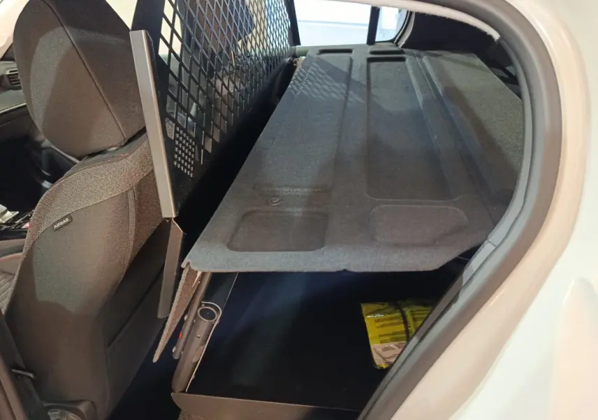 Vue intérieure côté droit du coffre de la Peugeot 208 électrique blanche avec tablette de coffre relevée et siège avant noir.