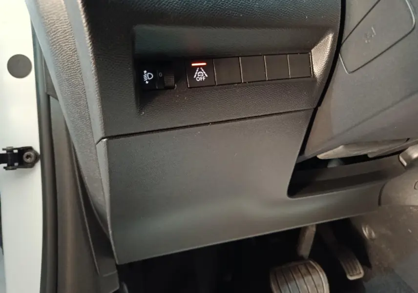 Vue rapprochée côté gauche du tableau de bord noir avec commandes d'assistance et pédales du Peugeot 208 blanc électrique.