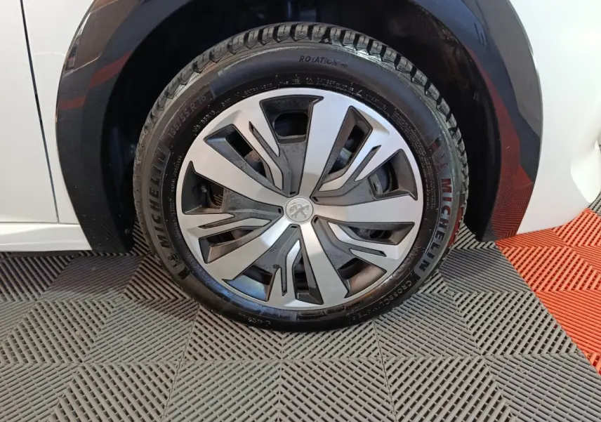 Gros plan sur la roue avant droite de la Peugeot 208 électrique blanche, avec jante alliage et pneu Michelin.