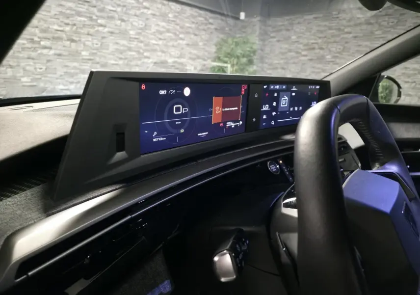 Vue intérieure du tableau de bord et volant noir du Peugeot 5008 hybride 2025 avec double écran panoramique HD flottant.