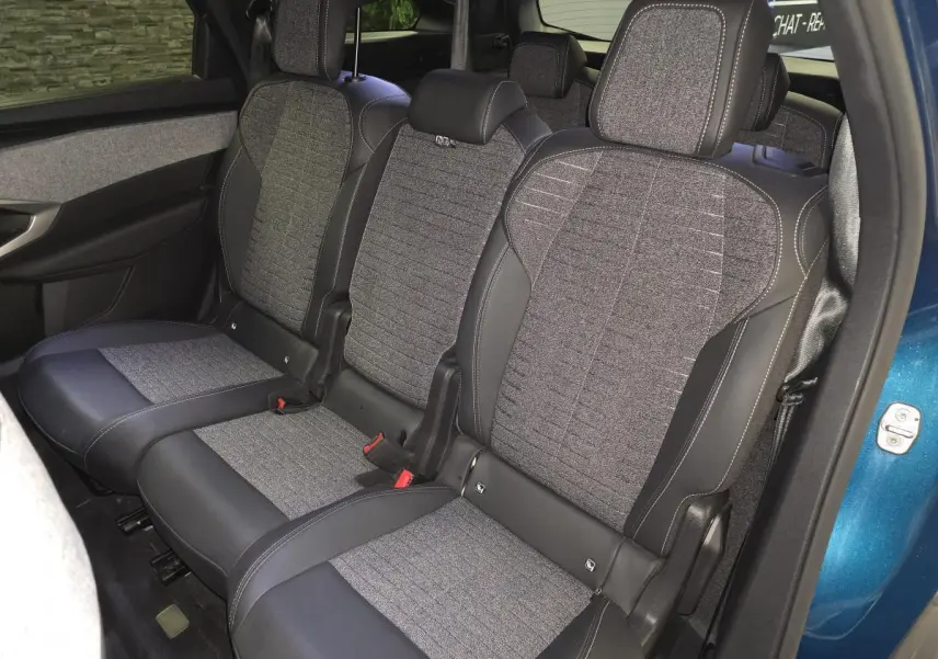 Vue intérieure côté gauche sur la banquette arrière tissu gris et cuir noir du Peugeot 5008 bleu 2025 hybride.
