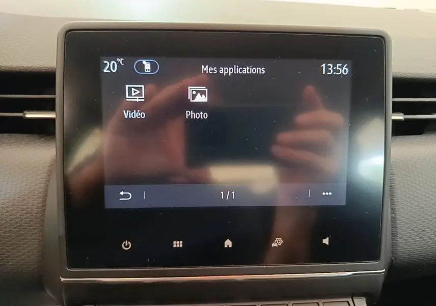 Écran tactile central affichant les applications vidéo et photo dans l'habitacle d'une Renault Clio gris foncé.