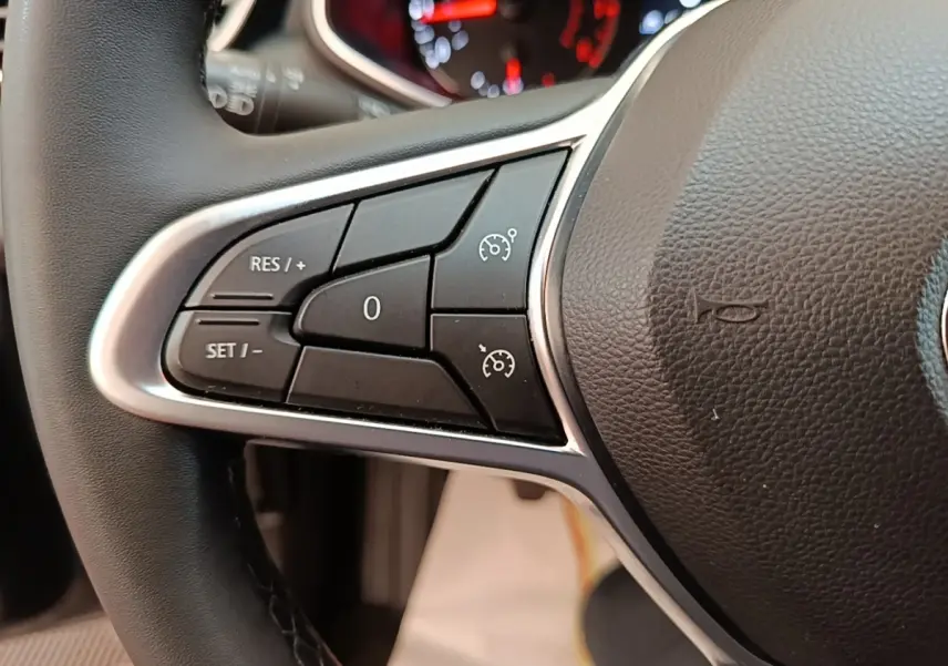 Gros plan sur les commandes du régulateur de vitesse au volant cuir noir de la Renault Clio Business TCe 100.