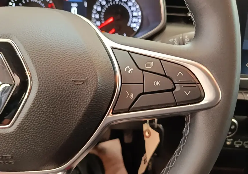 Gros plan sur le volant multifonctions en cuir synthétique de la Renault Clio Business TCe 100, avec commandes intégrées.