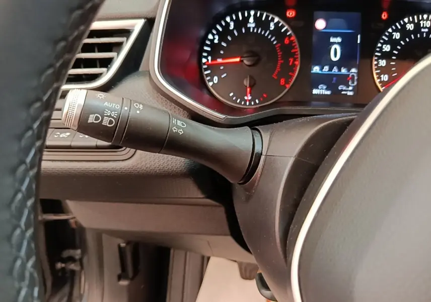 Vue rapprochée du tableau de bord et du commodo des phares d’une Renault Clio Business TCe 100, intérieur noir.