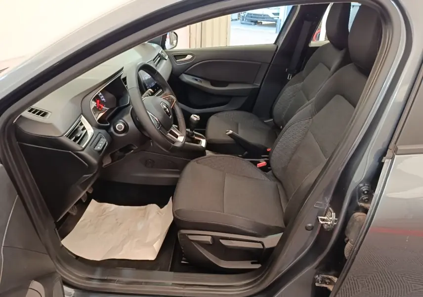 Intérieur côté conducteur d'une Renault Clio Business TCe 100 gris foncé, montrant sièges tissu et tableau de bord avec volant multifonctions.