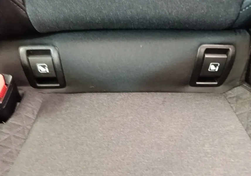 Détail des commandes de rabattement des sièges arrière sur la banquette d'une Renault Clio Business gris foncé.