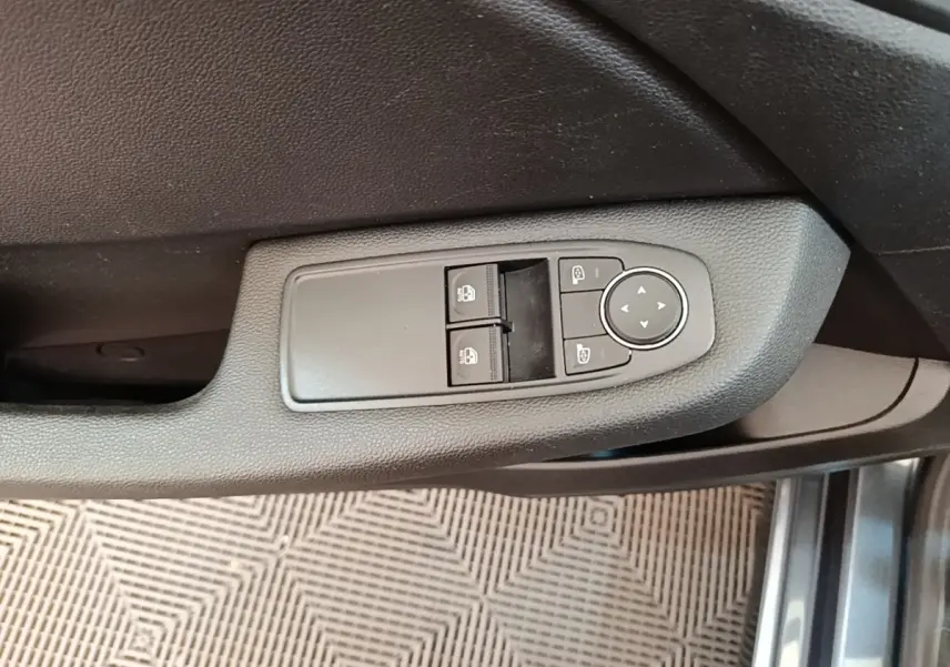 Commande des vitres et rétroviseurs sur la porte côté conducteur d'une Renault Clio Business TCe 100 gris foncé, vue intérieure rapprochée.