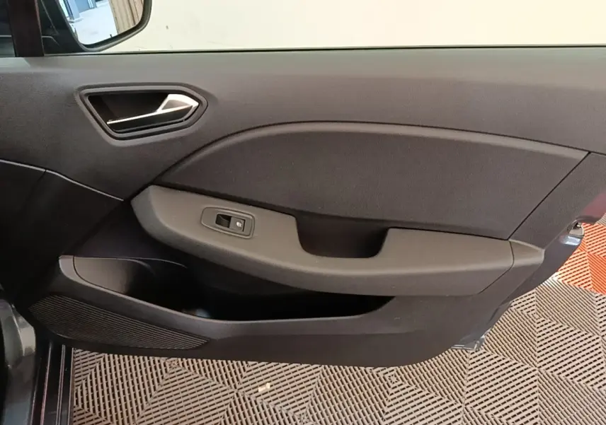 Gros plan sur la porte intérieure côté gauche de la Renault Clio Business TCe 100 gris foncé, avec poignée et commande de vitre.