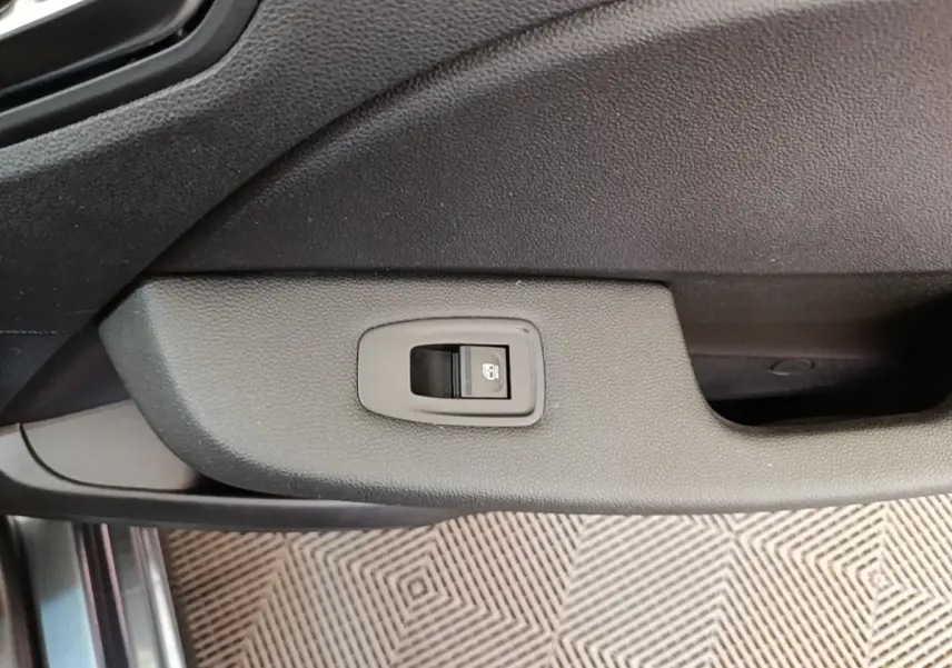 Détail de la commande de verrouillage centralisé sur la porte intérieure d’une Renault Clio Business TCe 100 gris foncé.
