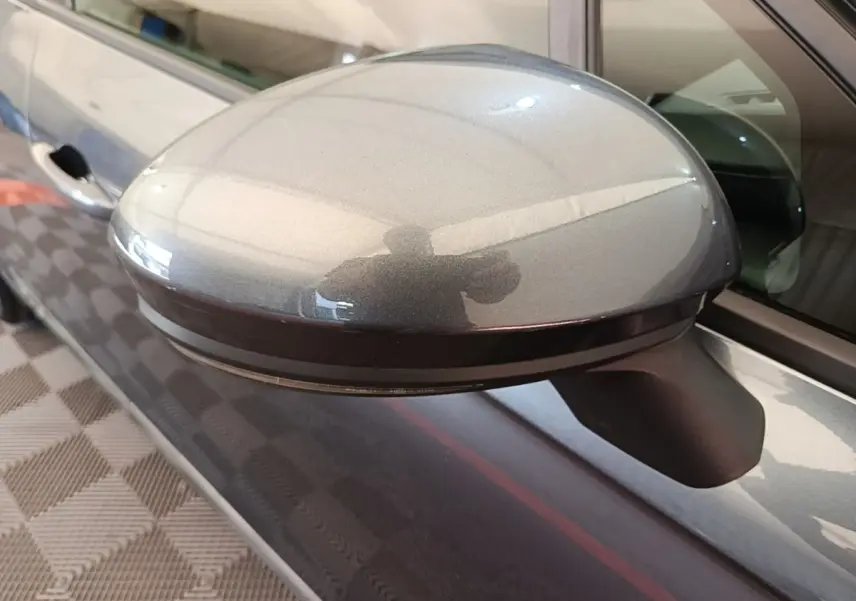 Rétroviseur côté gauche gris foncé de Renault Clio Business TCe 100, avec reflet et poignée de porte visible.
