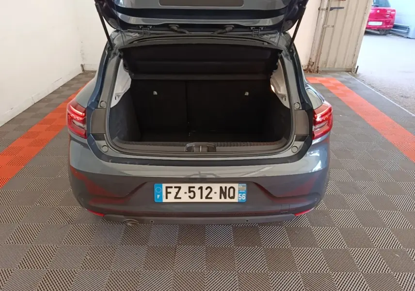 Vue arrière d'une Renault Clio Business TCe 100 gris foncé avec coffre ouvert dans un garage.