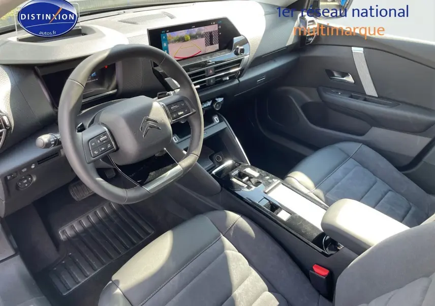 Intérieur du Citroën C4 2024 en gris, vue côté conducteur montrant volant, écran tactile et sièges cuir noir.