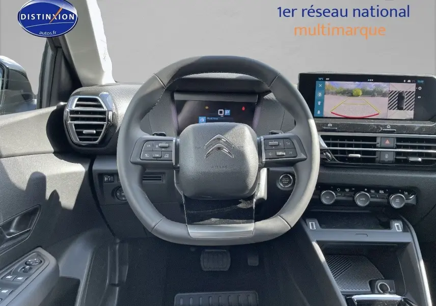 Vue frontale de l'intérieur de la Citroën C4 2024, volant cuir noir et écran tactile avec caméra de recul.