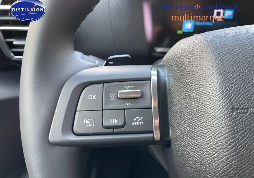 Gros plan sur les commandes au volant de la Citroën C4 gris platinium, mettant en valeur les boutons de régulateur et d'assistance.