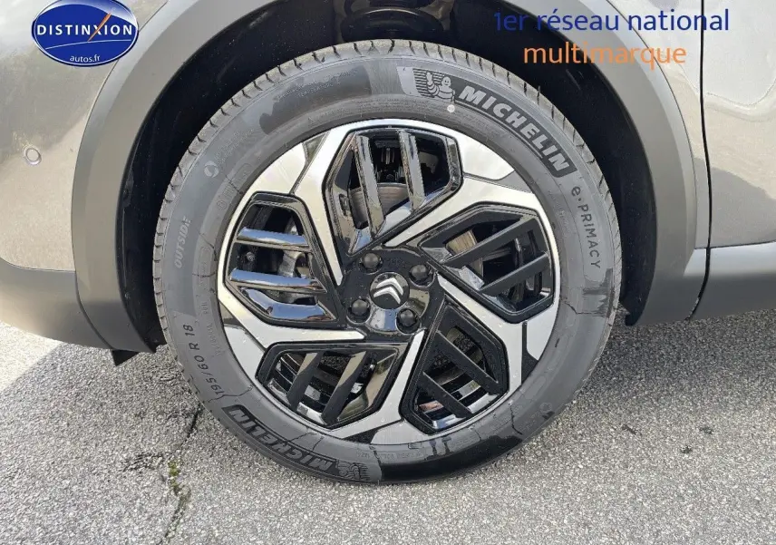 Gros plan sur la roue avant droite de la Citroën C4 gris platinium métal avec jante noire et argentée au design géométrique.