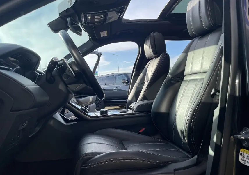 Intérieur du Range Rover Velar noir Santorini 2019, vue côté conducteur sur sièges cuir noirs et toit panoramique ouvert.