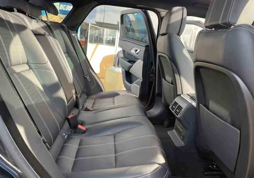 Vue intérieure arrière côté gauche du Range Rover Velar noir Santorini, sièges en cuir noir avec surpiqûres blanches.