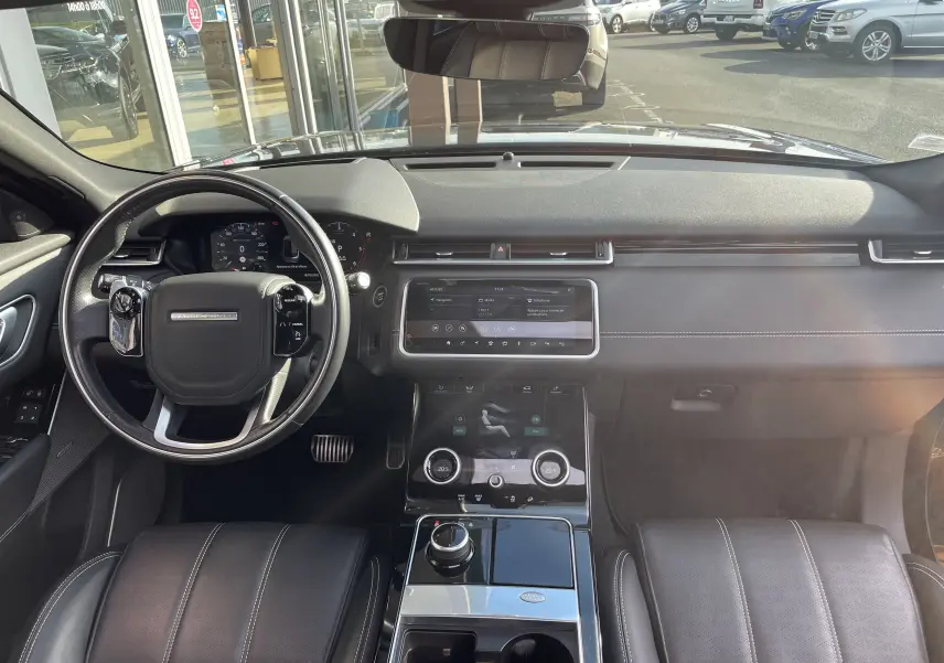 Vue intérieure du tableau de bord et volant noir du Range Rover Velar 2019, avec écran tactile et sellerie cuir noire.