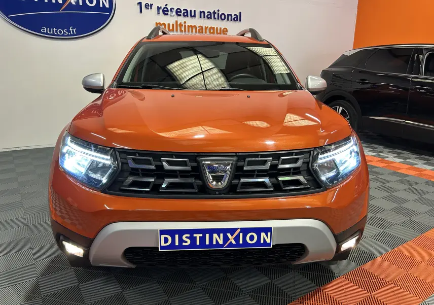 Vue frontale du Dacia Duster orange Arizona 2022 avec phares LED allumés et calandre noire distinctive.
