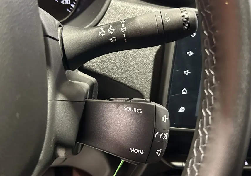 Gros plan sur la commande audio au volant du Dacia Duster 2022, avec tableau de bord et commandes d’essuie-glace visibles.