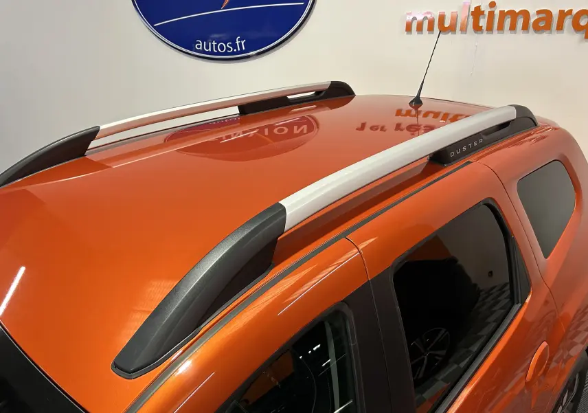 Vue en plongée sur le toit orange Arizona d'un Dacia Duster 2022 avec barres de toit grises et vitres teintées.