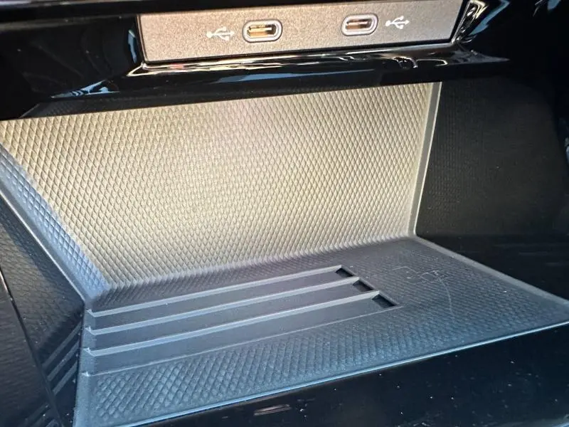 Gros plan sur la zone de recharge sans fil et ports USB-C du Volkswagen Golf noir 2025, version R-Line Edition.