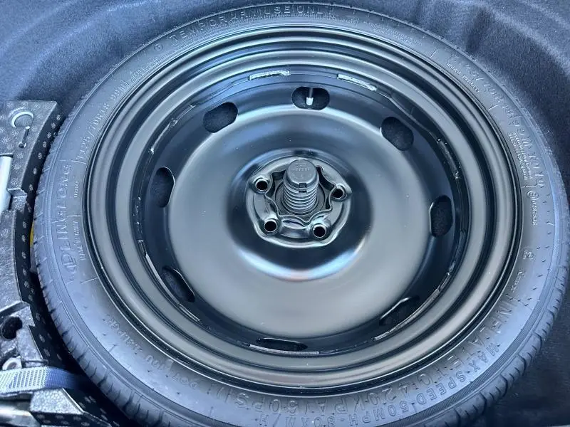 Gros plan sur la roue de secours noire du coffre d'une Volkswagen Golf 1.5 eTSI EVO2 150ch R-Line Edition 2025.