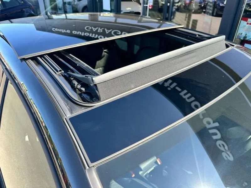 Toit ouvrant panoramique ouvert sur une Volkswagen Golf noire 2025, vue rapprochée du dessus côté gauche.