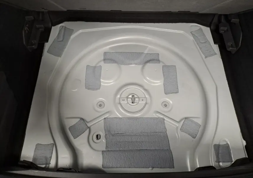 Vue plongeante sur le coffre ouvert d'une CUPRA TERRAMAR blanc Nevada, montrant le logement de roue de secours vide.