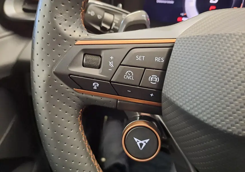 Gros plan sur la partie gauche du volant perforé avec commandes noires et détails cuivrés du CUPRA TERRAMAR 2025.