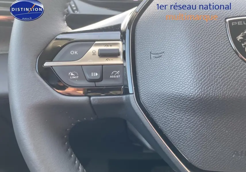 Gros plan sur le volant noir de la Peugeot 308 SW gris sellenium, avec commandes multifonctions visibles à gauche.