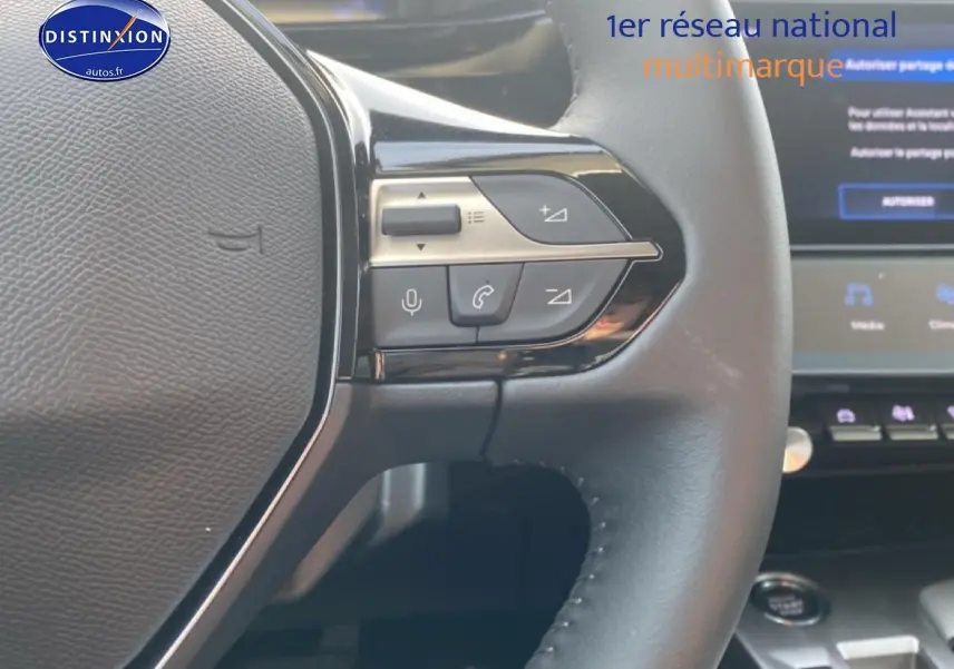 Gros plan sur le volant multifonction noir de la Peugeot 308 SW 1.2 hybrid 145 allure e-dcs6 avec commandes audio intégrées.