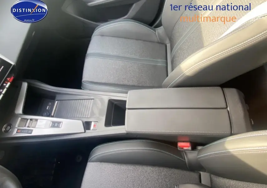 Vue intérieure en plongée du tunnel central et accoudoir noir du Peugeot 308 SW gris sellenium, avec console moderne et sièges tissu.