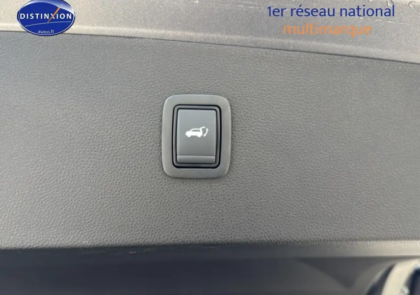 Bouton d'ouverture du hayon sur la garniture intérieure noire du coffre du Dacia Bigster gris schiste.