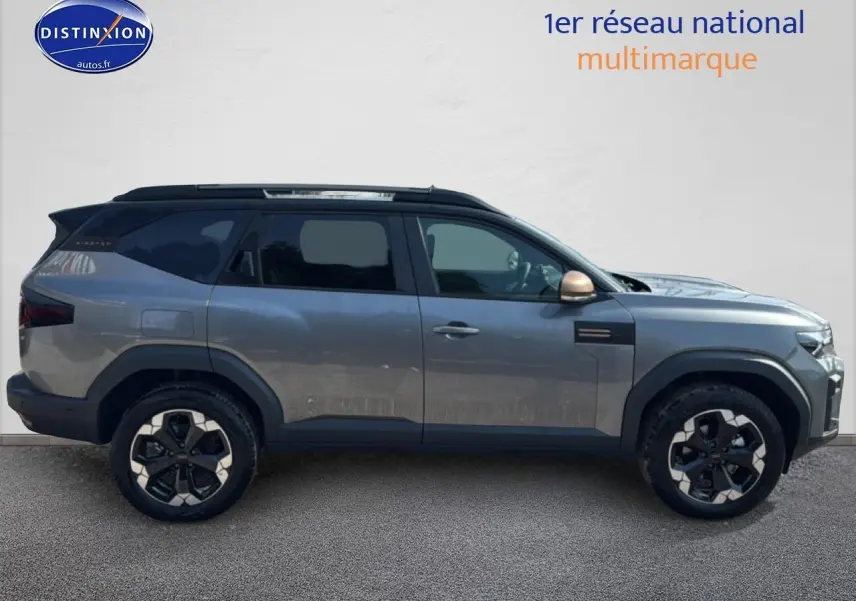Profil droit du Dacia Bigster gris schiste avec jantes alu et toit noir contrasté sur fond neutre.