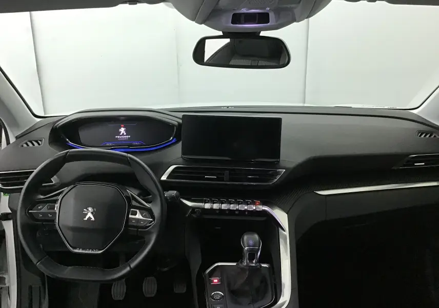 Intérieur du Peugeot 5008 2021 en vue frontale, tableau de bord noir avec écran central et volant compact multifonction.