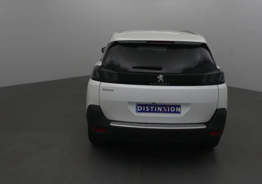 Vue arrière d'un Peugeot 5008 blanc nacré avec vitres teintées et logo Peugeot visible sur le hayon.