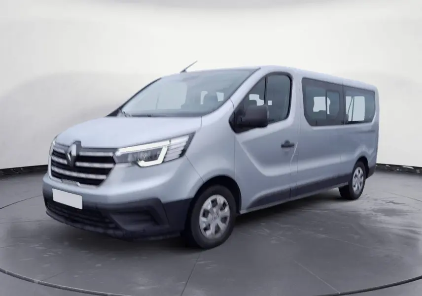 Renault Trafic Combi gris clair métal vu en 3/4 avant droit, avec calandre noire et vitres latérales teintées.