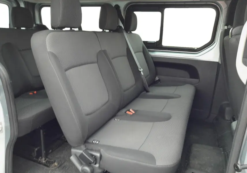 Vue intérieure latérale droite des sièges arrière gris foncé du Renault Trafic Combi L2 2023, montrant trois places avec appuie-têtes.