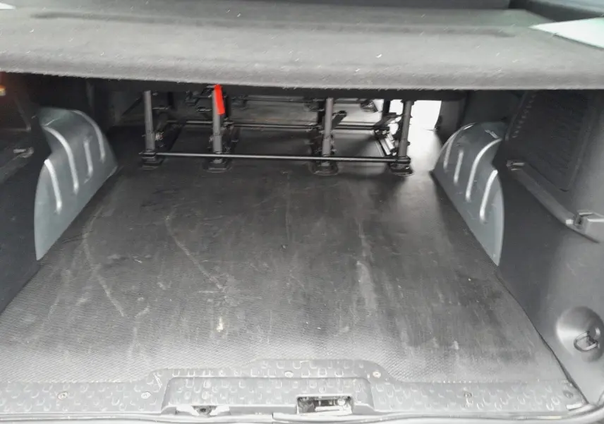 Espace de chargement vu de l'arrière du Renault Trafic Combi gris clair, avec plancher caoutchouté et structure métallique sous les sièges.
