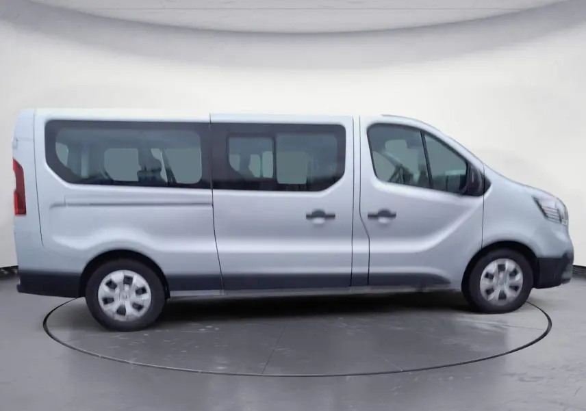 Profil côté droit du Renault Trafic Combi gris clair métal 2023, montrant ses grandes fenêtres et portes coulissantes.