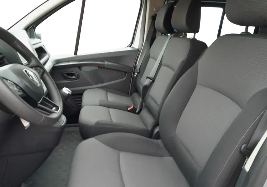 Vue intérieure côté conducteur du Renault Trafic Combi 2023, sièges gris foncé en tissu et volant multifonction.