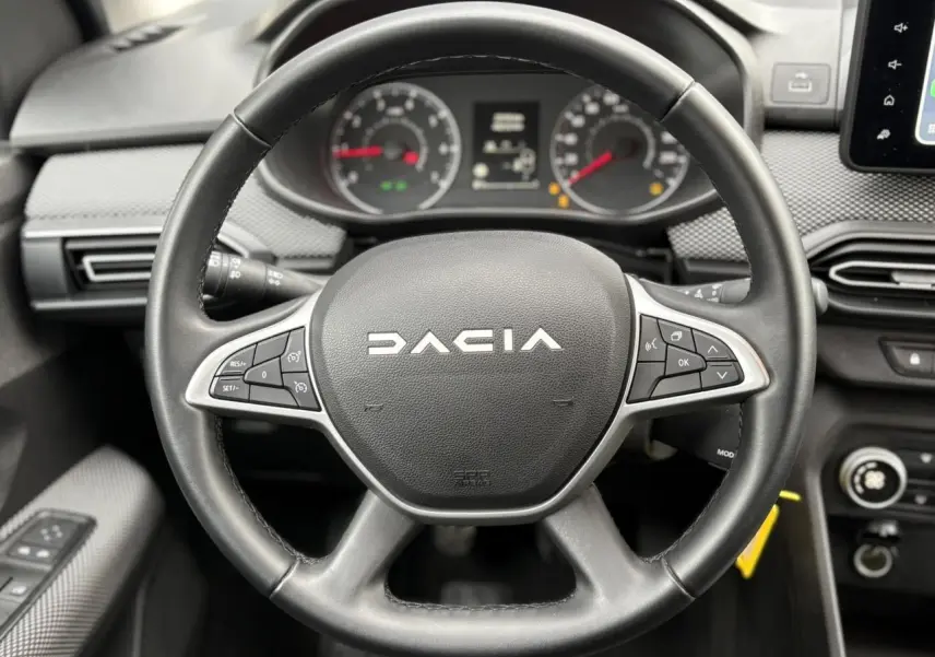 Vue rapprochée du volant noir de la Dacia Jogger 2025 avec tableau de bord et commandes au volant visibles.