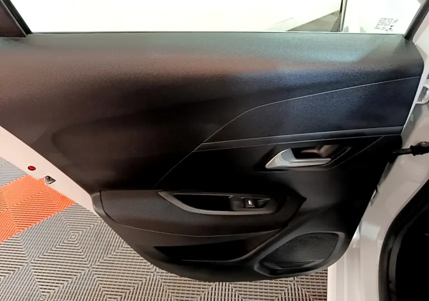 Vue intérieure côté gauche de la porte arrière noire d’une Peugeot 208 Electrique Active Business blanche.