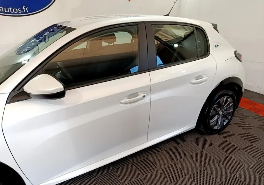Vue latérale droite d'une Peugeot 208 électrique Active Business blanche, avec jantes alliage et rétroviseurs assortis.