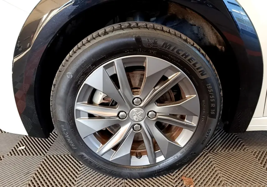 Gros plan sur la roue avant droite avec jante alliage grise et pneu Michelin d'une Peugeot 208 blanche.