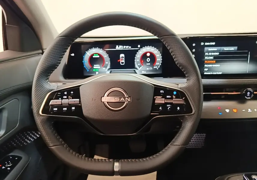 Vue frontale du volant cuir noir multifonctions de la Nissan Ariya 63kWh avec tableau de bord numérique et écran tactile.