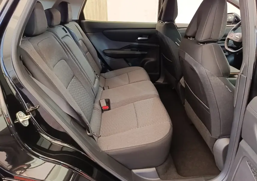 Vue intérieure côté gauche montrant la banquette arrière grise du Nissan Ariya noir 2026 avec sièges tissu et ceintures visibles.