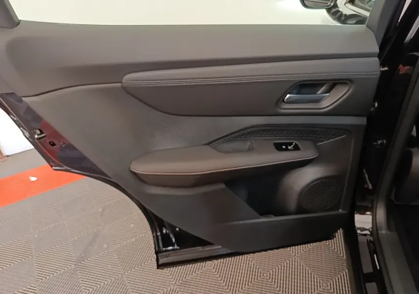 Vue rapprochée de la porte arrière droite noire du Nissan Ariya 2026 avec accoudoir en cuir et commande de vitre.